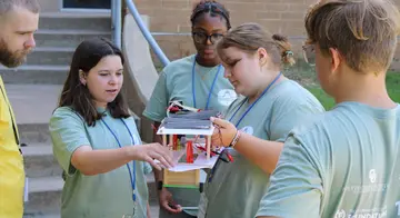 Students gather around a mini solar-powered vehicle