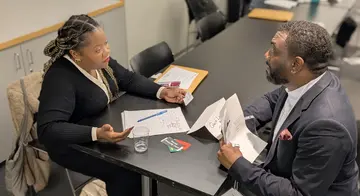 A woman sits across a table from a man at a previous reentry simulation workshop
