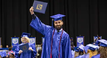 Abraan Lopez hold his degree above his head at commencement.