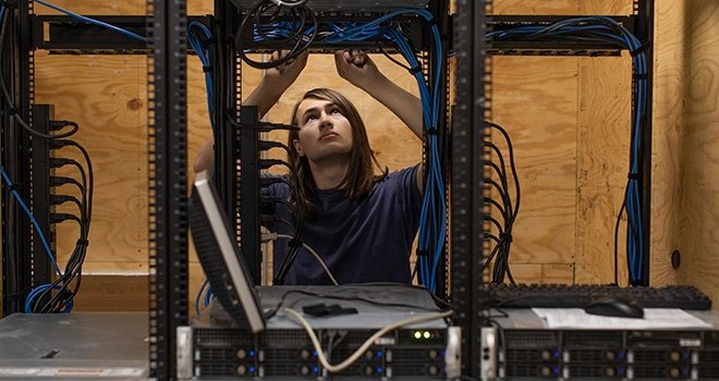 Young man works on server in a server room.