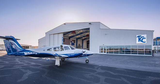 blue and white tcc single engine plane sits parked in front of the TCC Riverside Aviation Center.