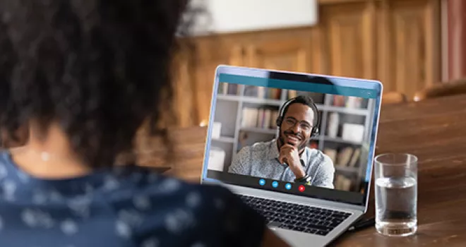 Over the shoulder view of a student receiving assistance remotely from home.