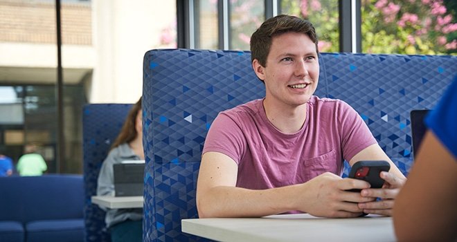 Young mans sits across from a companion at a table in the Southeast campus dining area.