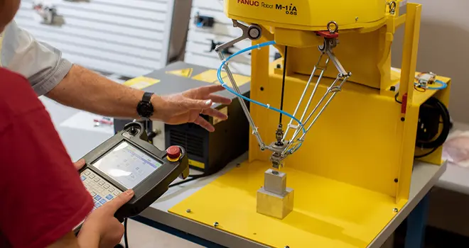 TCC student operates manufacturing robot.