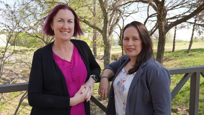 TCC psychology professors Dr. Jen Ivie and Dr. Alicia MacKay pose together outside.