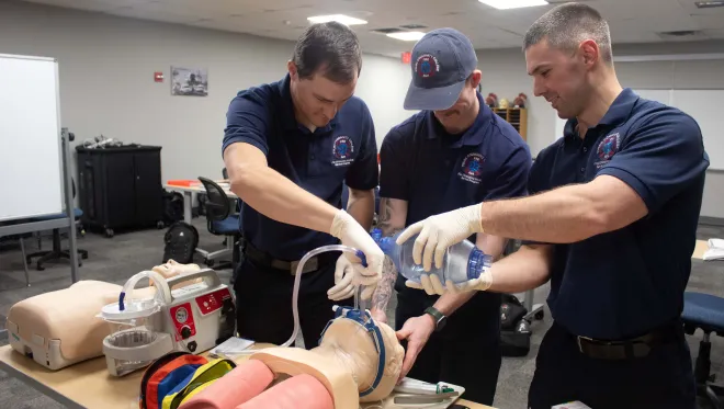 Three students work on a medical manikin