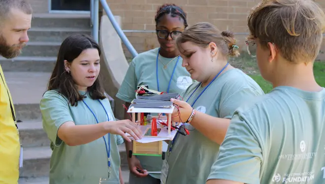 Students gather around a mini solar-powered vehicle