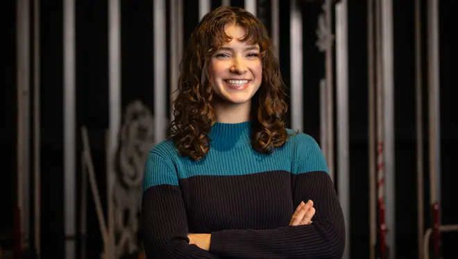 Moriah Jestus smiles at the camera with her arms crossed