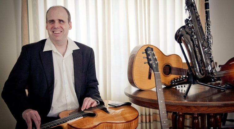 Rory Hoffman is sitting with a guitar in his lap. 