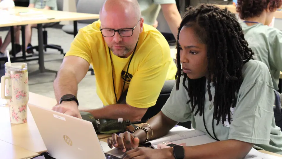 TCC instructor and student look at laptop screen