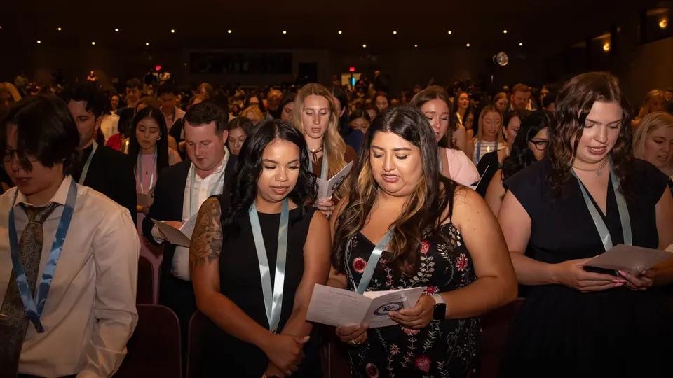 A crowd of students reads the Nightingale Pledge from a pamphlet