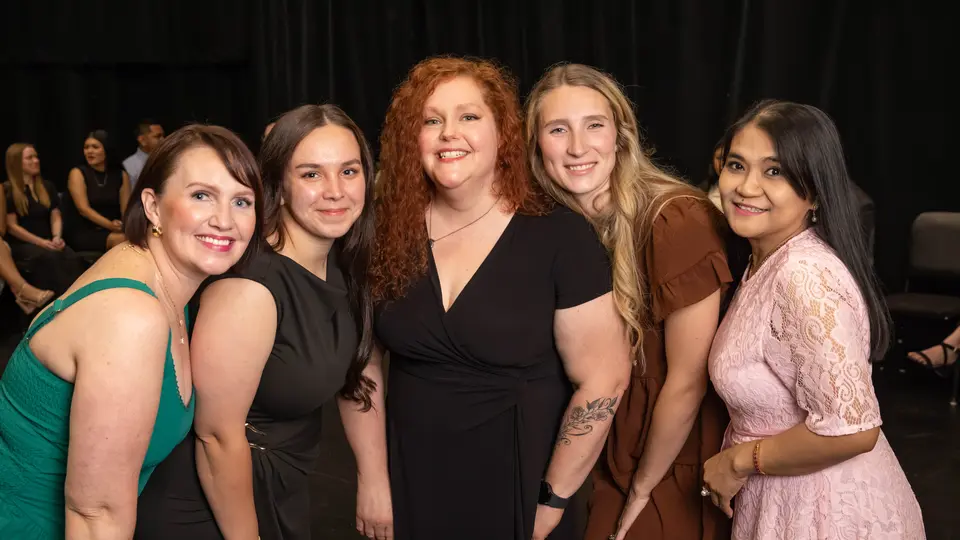 A group of five women are posing and smiling before the ceremony.