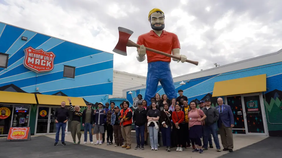 A group of about 30 people stand in frnt of the Meadow Gold Mack statue