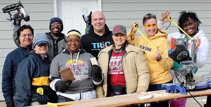 A group of TCC TRIO students posing with power tools at habitat for humanity build site.