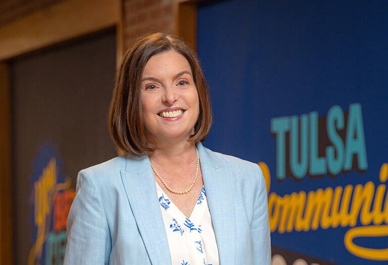 TCC president Leah Goodson smiles, wearing a light blue suit jacket and floral shirt..