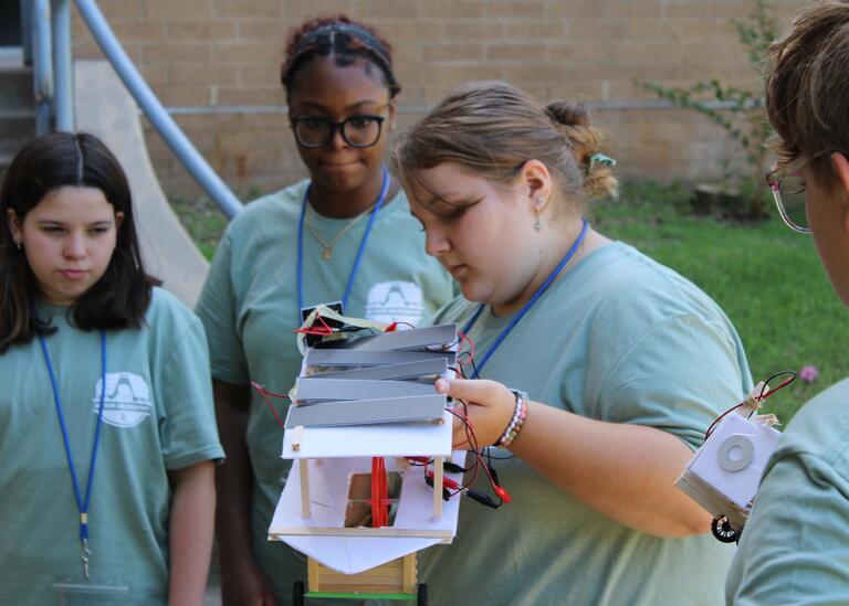 Students gather around a mini solar-powered vehicle
