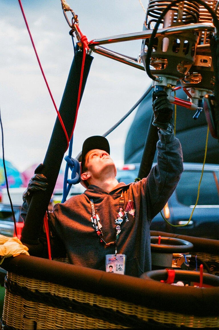 Baylor Rodden is in a hot-air balloon basket and looking up into the balloon